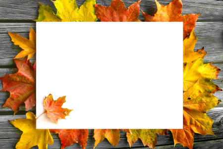 Blank white mockup surrounded by brightly colored autumn leaves on wooden background