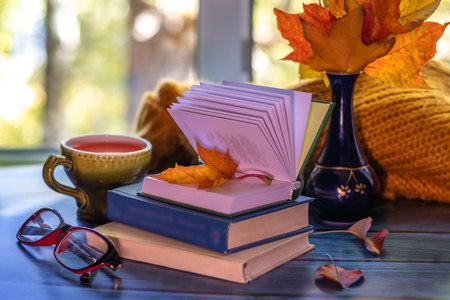 Books and tea in cozy autumn setting by window. Fall teatime.