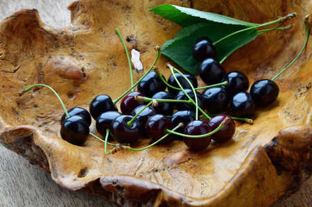 Ripe cherry in a wooden vase. Wooden bowl with ripe cherries.の写真素材