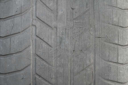 Old black tire with worn tread and cracks, worn old car tire tread, old damaged, worn black tire tread, large cracks in the car wheel, tire black color for background.の写真素材