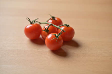 Fresh tomatoes on a branch, on a new wooden table.の写真素材