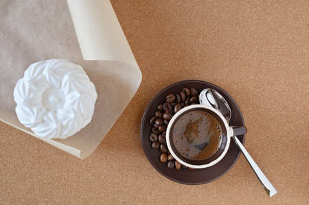 Fresh meringue cake on parchment and espresso coffee with chrome spoon on cork napkin.の写真素材