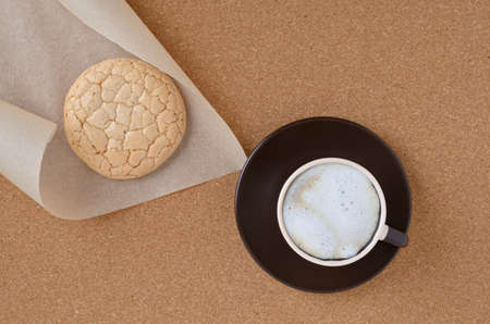 Macaroons on parchment and cappuccino coffee on a cork napkin.の写真素材