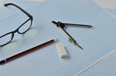 Compass, pencil, and eraser points on the blue graph paper for sketching.の写真素材