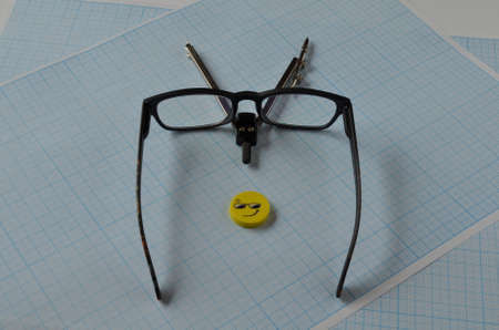 A compass, goggles and a yellow eraser on graph paper for drawing.の写真素材