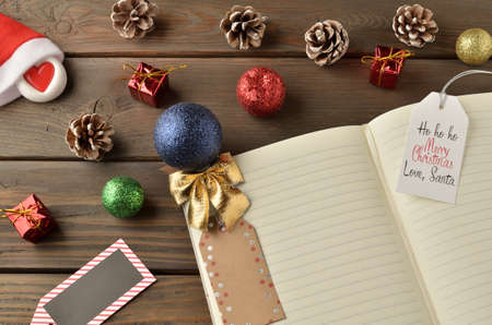Christmas decorations, star and balls on wooden table. Notebook for new year greetings. Festive decoration, on a brown wooden table with space for text.の写真素材
