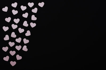 Floating pink hearts. Small scattered hearts on a black background with space