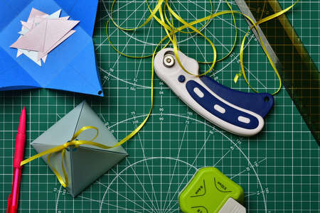 Top view of a homemade gift wrap for scrapbooking with a ruler, pencil and roller knife, on a green cutting Mat.の写真素材