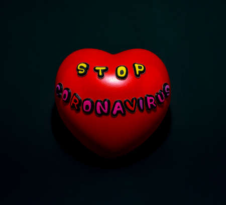 A red heart with the words stop coronavirus on a black background.の写真素材