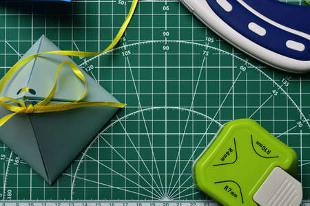 Homemade gift box with a curly stapler and a roller scrapbooking knife, on a green cutting mat.の写真素材