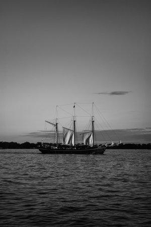 Old sailboat on the lake at sunset. Black and white photo. Toronto, Canada.
