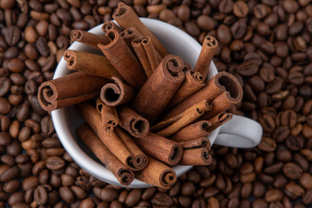 Coffee beans and cinnamon sticks in a cup. Food drink background.の写真素材