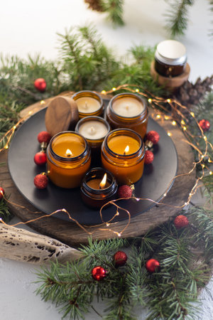Soy candles burn in glass jars. The evening is dark. Aromatherapy and relaxation. Comfort at home. Candle in a brown jar. Scent and light. Scented handmade candle. Aroma therapyの写真素材