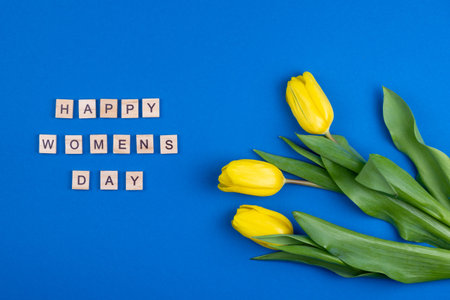 Happy womens day card. Wooden letters. Three yellow spring tulips flowers. Background with flowers...