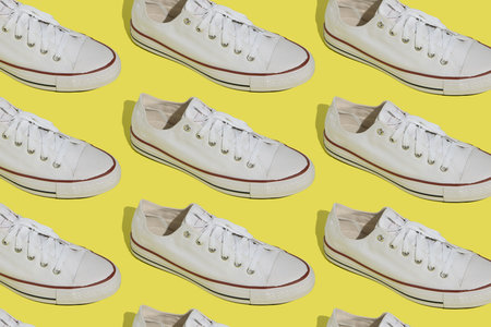 White sneakers pattern. Sports casual shoes on a yellow background. Top view.