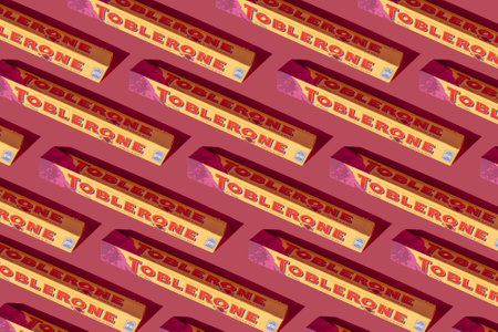 Toblerone Swiss chocolate bar with nuts. New package with mountain logo on pink background. Candy sweets are a classic souvenir from Switzerland. Kyiv, Ukraine - July 10, 2023.のeditorial素材