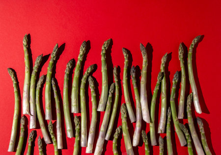 Green asparagus on red background. Vegetable food top view. Sprouts stems. Naturalの写真素材