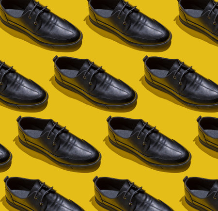 Shoe pattern. Black shoes on yellow background top view. Accessories concept. New leather shoes. Classic office style. Mens shoe.の写真素材