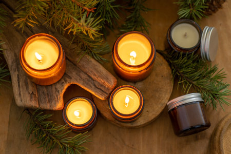 Soy candles burn in glass jars. The evening is dark. Aromatherapy and relaxation. Comfort at home. Candle in a brown jar. Scent and light. Scented handmade candle. Aroma therapyの写真素材
