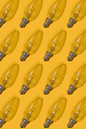Yellow background. Electric light bulbs pattern. An old glass electric light bulb with a tungsten...