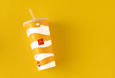 Yellow glass of McDonalds. Paper cup with lid. Takeaway drink. McDonalds logo. Ukrainian, Kyiv - March 02, 2023.のeditorial素材