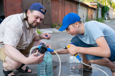 Dad and teenage son work together on the street near the garage. Outdoor activity. Family spend...