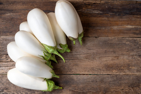 Harvest white eggplants on a wooden background with place for text. Eggplant vegetable on the table. Food with copy space.の写真素材