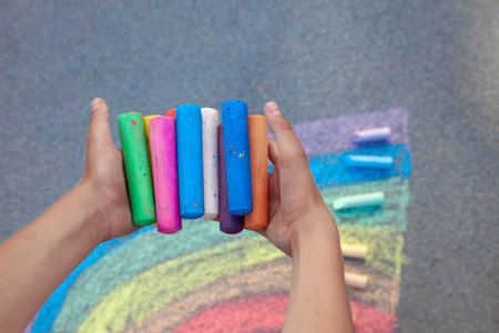 Chalks. Large multi-colored crayons in children's hands. The child holds the chalk. Draw on the street. Fascinating drawing for children.の写真素材