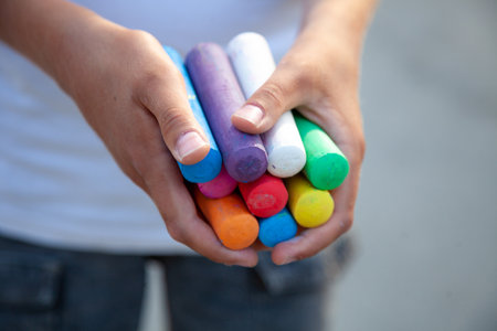 Chalks. Large multi-colored crayons in children's hands. The child holds the chalk. Draw on the street.の写真素材