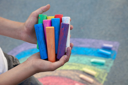 Sidewalk chalks. Colored crayons in children's hands. The child holds the chalk. Draw on the street. Painting activitiesの写真素材