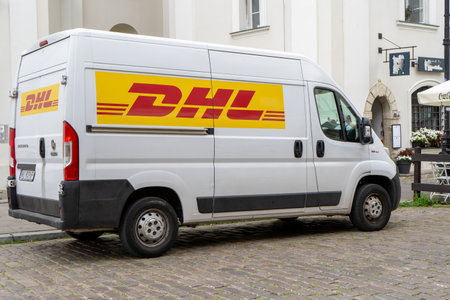 Delivery by DHL. White minibus on the street, delivery of settlements and documents. Poland, Warsaw - July 26, 2023のeditorial素材