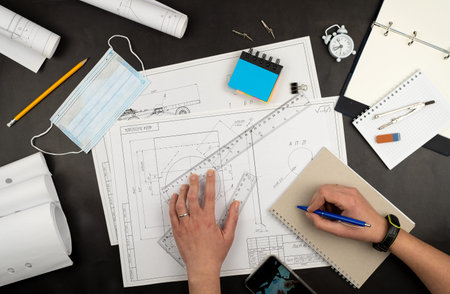 Mechanical drawing on sheets of paper. Hands on the table top view. Workflow of an architect,...