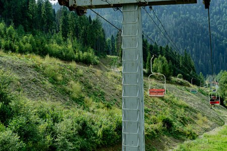 Ski lift in green forest. Cableway in Mountains. Summer nature.