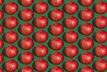 Pomegranate pattern. Red pomegranates on a green background. Fruit food.の写真素材