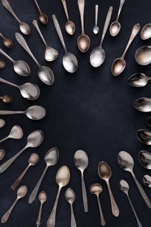 Set of different spoons. Silver cutlery on a black background. Spoon on the tableの写真素材