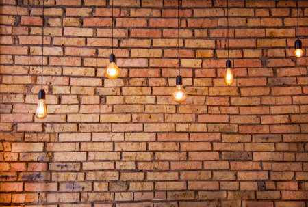 Old electric incandescent lamps with tungsten filament. Against the backdrop of a brick wall. Texture of old stone background.の写真素材