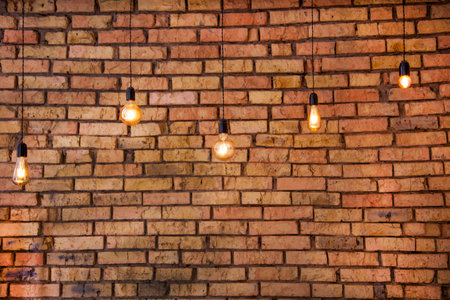 Old electric incandescent lamps with tungsten filament. Against the backdrop of a brick wall. Texture of old stone background.の写真素材