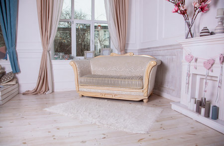 An old sofa with wooden planks by the window. Empire style furniture. Light white room interior.の写真素材