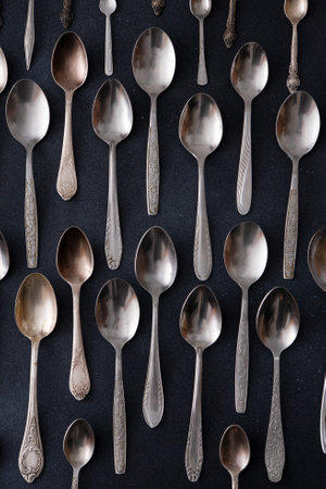 Set of different spoons. Silver cutlery on a black background. Spoon on the tableの写真素材