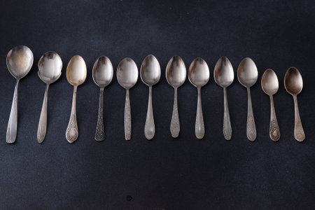 Set of different spoons. Silver cutlery on a black background. Spoon on the tableの写真素材