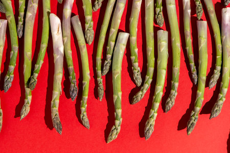 Green asparagus on red background. Vegetable food top view.の写真素材