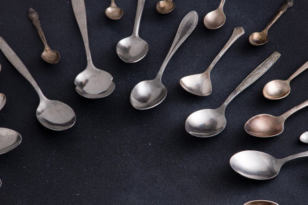 Set of different spoons. Silver cutlery on a black background. Spoon on the tableの写真素材