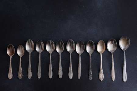 Set of different spoons. Silver cutlery on a black background. Spoon on the tableの写真素材