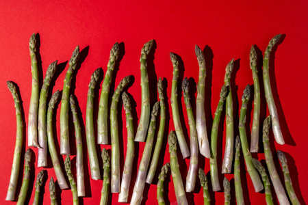 Green asparagus on red background. Vegetable food top view.の写真素材