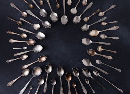 Set of different spoons. Silver cutlery on a black background. Spoon on the tableの写真素材