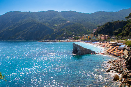 Umbrellas on the beach in summer. Italian holidays on the coast of the Ligurian blue Sea and Mountain rock. Liguria Monterosso.の写真素材