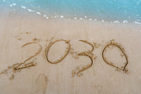 2030 numbers written in the sand. Sea wave beach