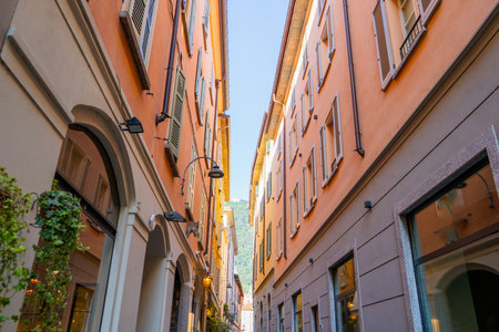 Narrow Italian street in Como city. Multicolor old house building architectureの写真素材