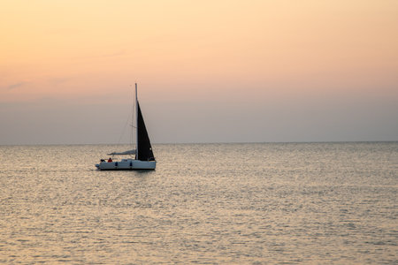 Yacht ship is sailing. Calm coast. Evening sky. Sunset sea water horizon.の写真素材