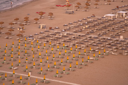 Italy resort top view. Wide sandy beach with sun loungers and umbrellas. Evening on the Rimini coast. Empty seashoreの写真素材